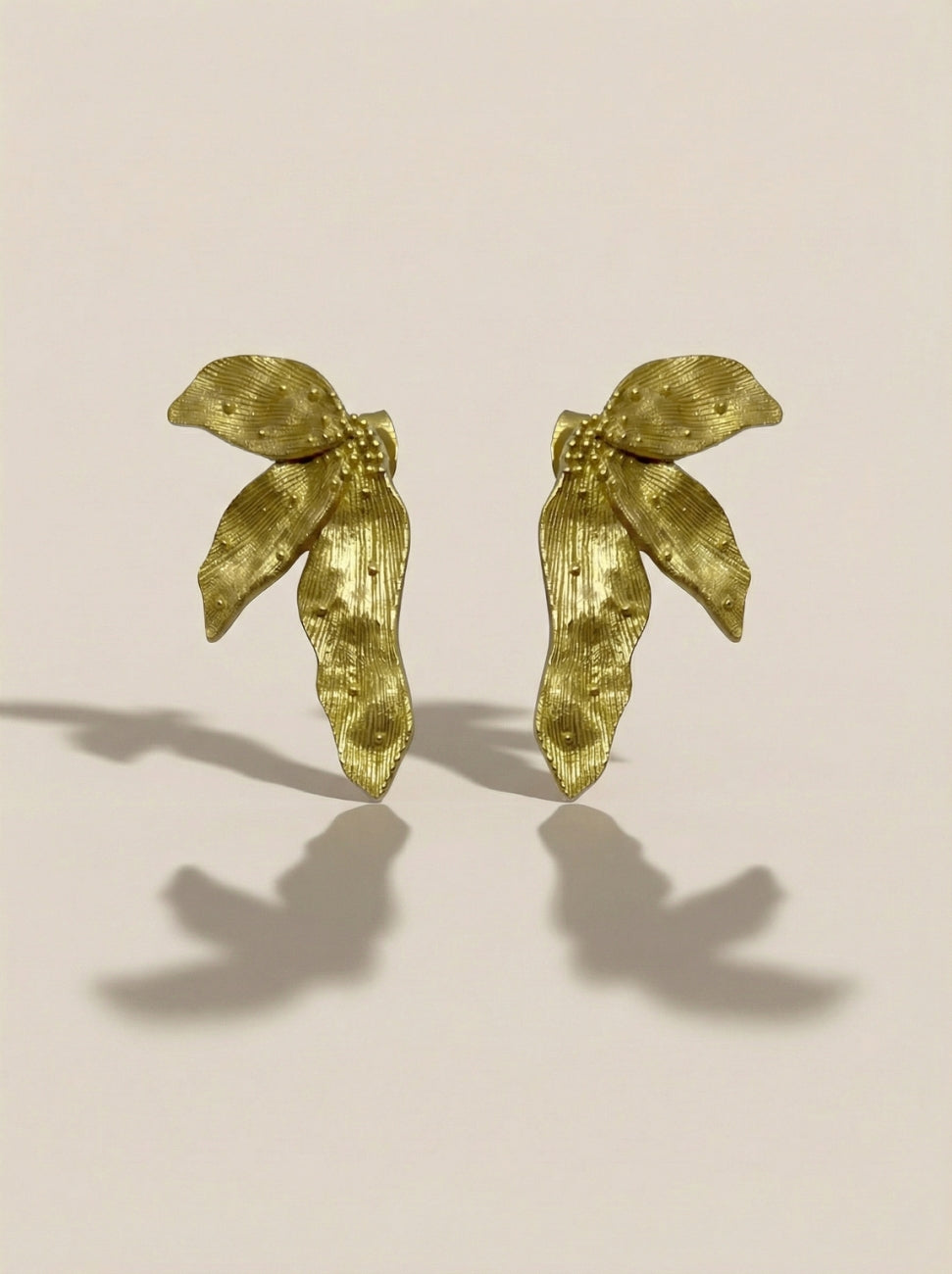 A pair of textured gold leaf-shaped earrings from rhodium with antique gold plating