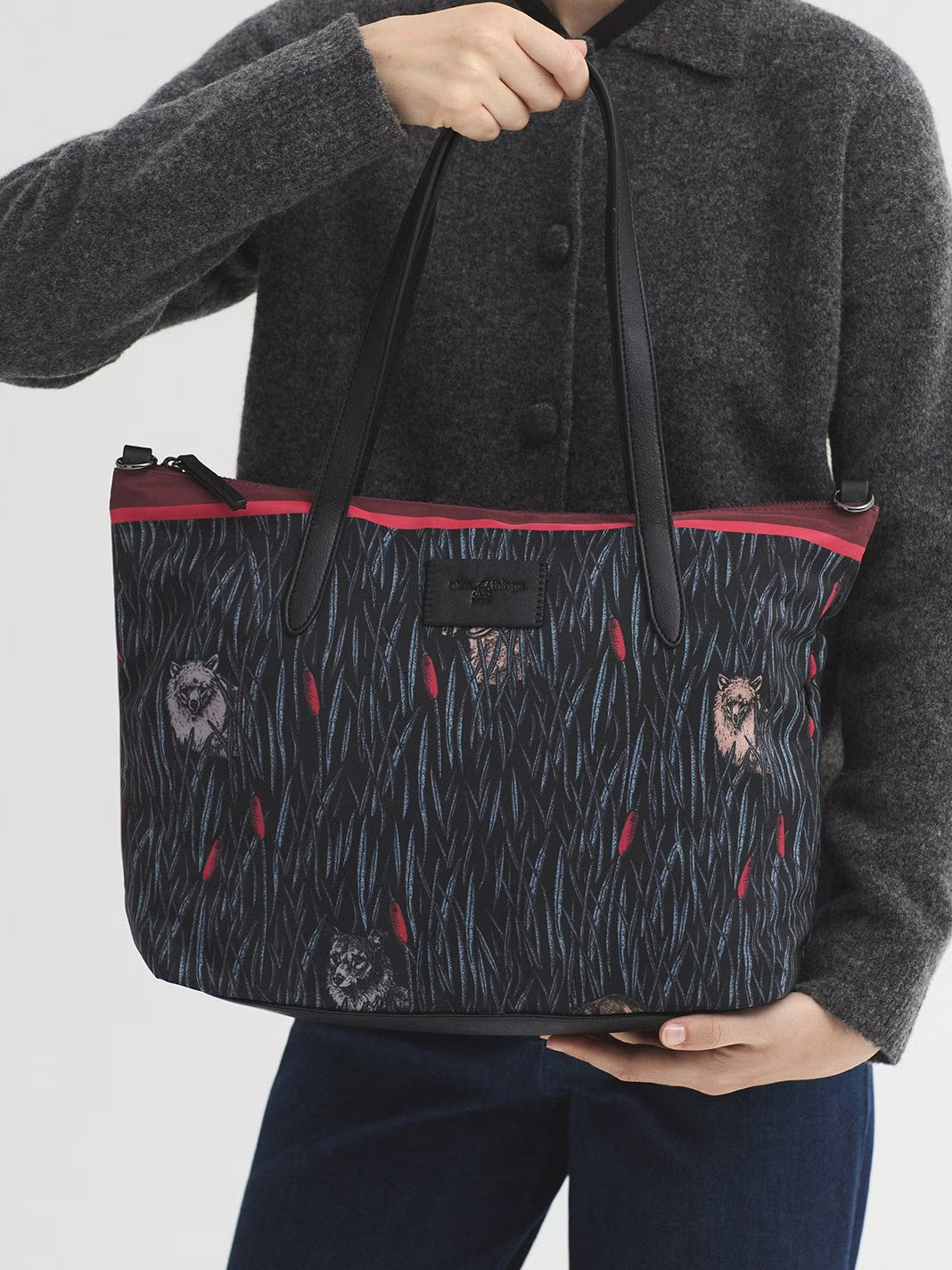 Printed black shopping bag from the collection featuring a zip top fastening and inside pockets. Adjustable strap so it can be used as a crossbody bag. The design is finished off with a logo patch, 30 cm tall x 34cm long x 14 cm deep.