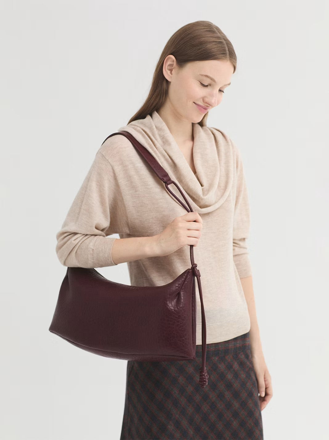 Debossed bordeaux bag with an adjustable strap and knot detail. Featuring a zip top fastening and inside pockets. The design is finished off with a logo, 44 cm long x 20 cm high x 10 cm deep at the base.