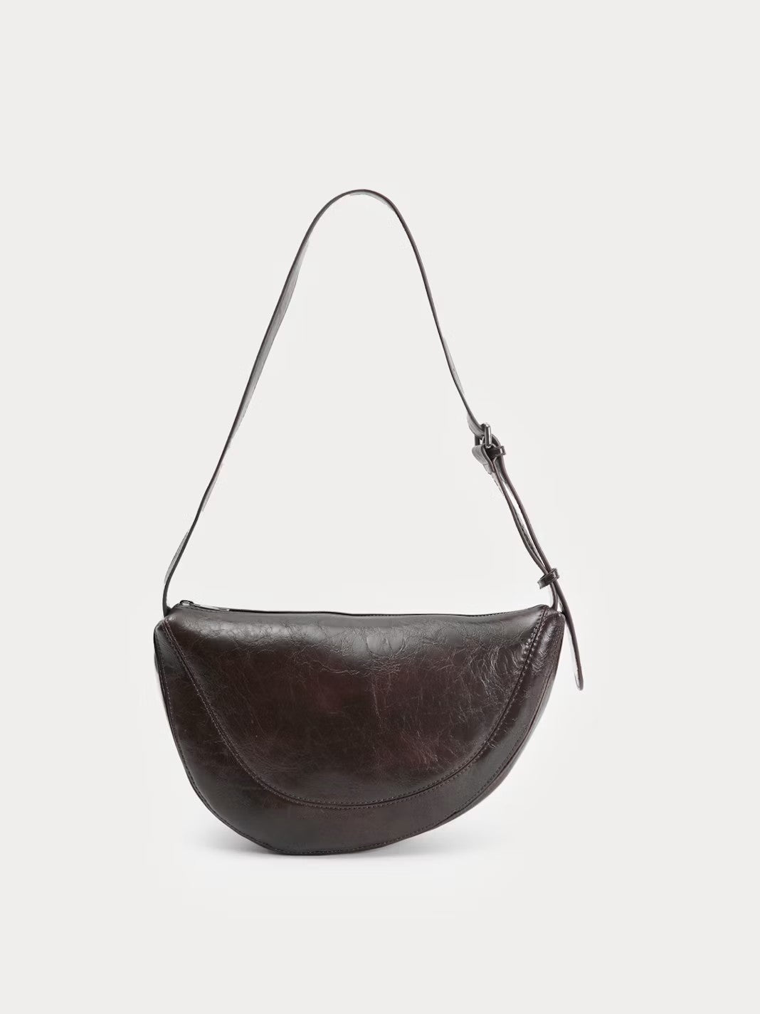 Half moon chocolate crossbody bag with an irregular design made of eco-leather. Featuring a metal zip top fastening with a pull tab with logo. With adjustable strap with buckle so the fit can be adjusted as needed. Inside pockets, 29 cm long x 17 cm high x 7 cm deep.