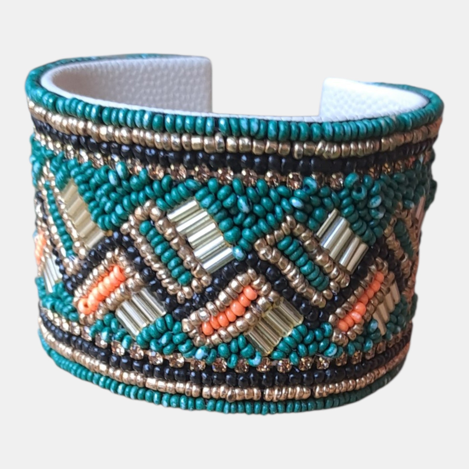 A wide cuff bracelet made of turquoise, navy, silver, and orange seed beads in a geometric pattern, with a white textured inner lining, Measurements: 4,5cm wide, 18cm circumference