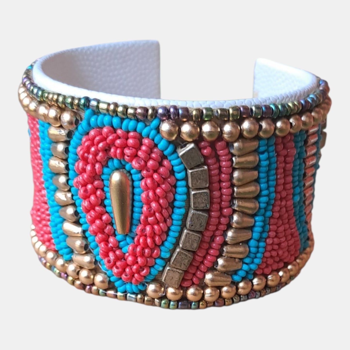 A wide cuff bracelet featuring intricate beaded patterns in turquoise blue, pink, and metallic gold, with a textured white inner band, Measurements: 4,5cm wide, 18cm circumference