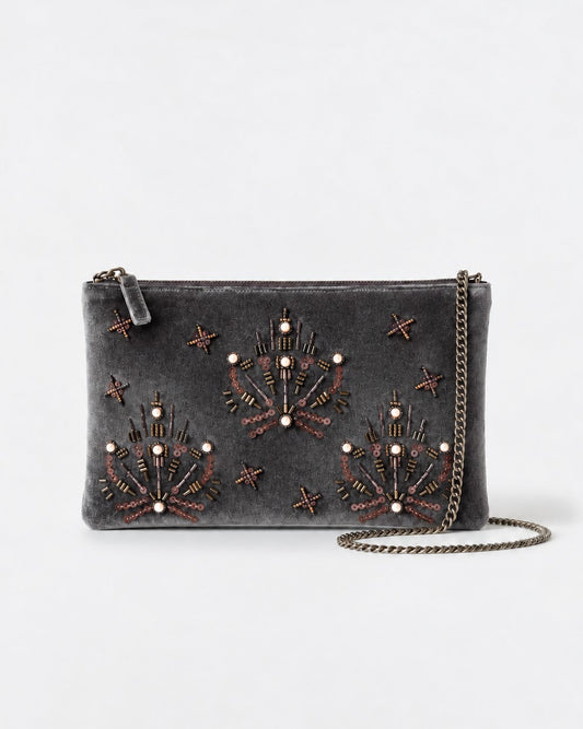 Flat brown clutch hand-embroidered with beads, bugle beads and pearls tracing jewel motifs and stars. Soft velvety viscose fabric, with a detachable chain strap and wrist loop. Inner pocket. 27,5cm x 17cm x 1cm