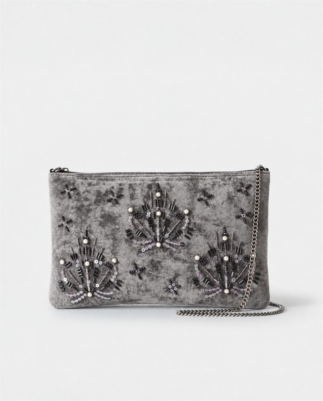 Flat grey clutch hand-embroidered with beads, bugle beads and pearls tracing jewel motifs and stars. Soft velvety viscose fabric, with a detachable chain strap and wrist loop. Inner pocket. 27,5cm x 17cm x 1cm