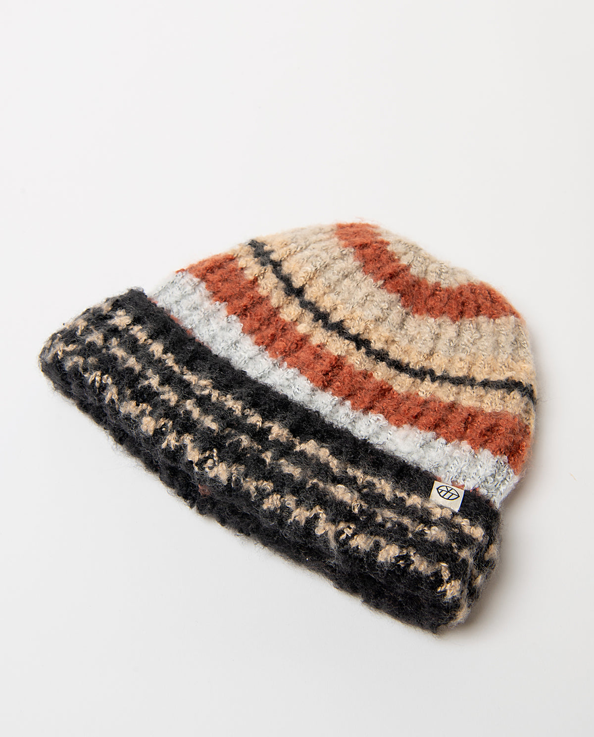 Chunky beige knit beanie with a wide contrast turn-up and bouclé texture. The top features warm multicolored jacquard stripes.