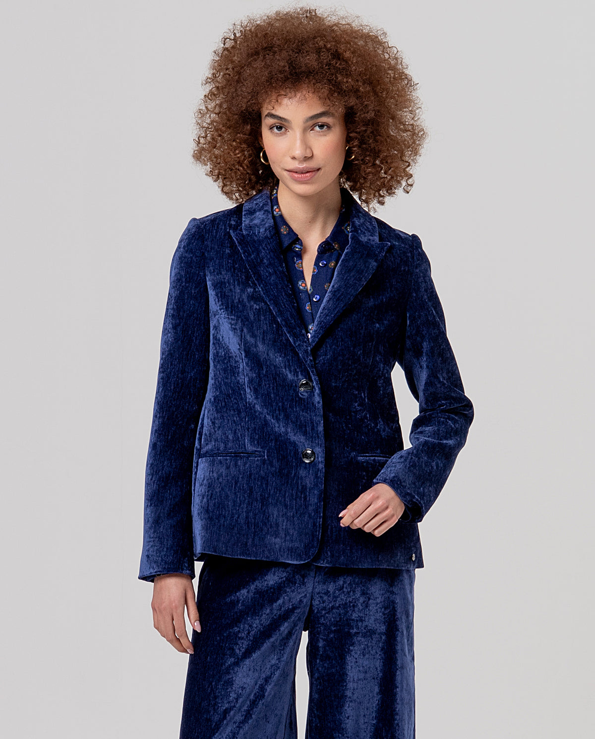 Fitted blazer blue with lapels and a two-button closure, in velvet with a soft feel and subtle sheen. Piped pockets and a flattering silhouette.
