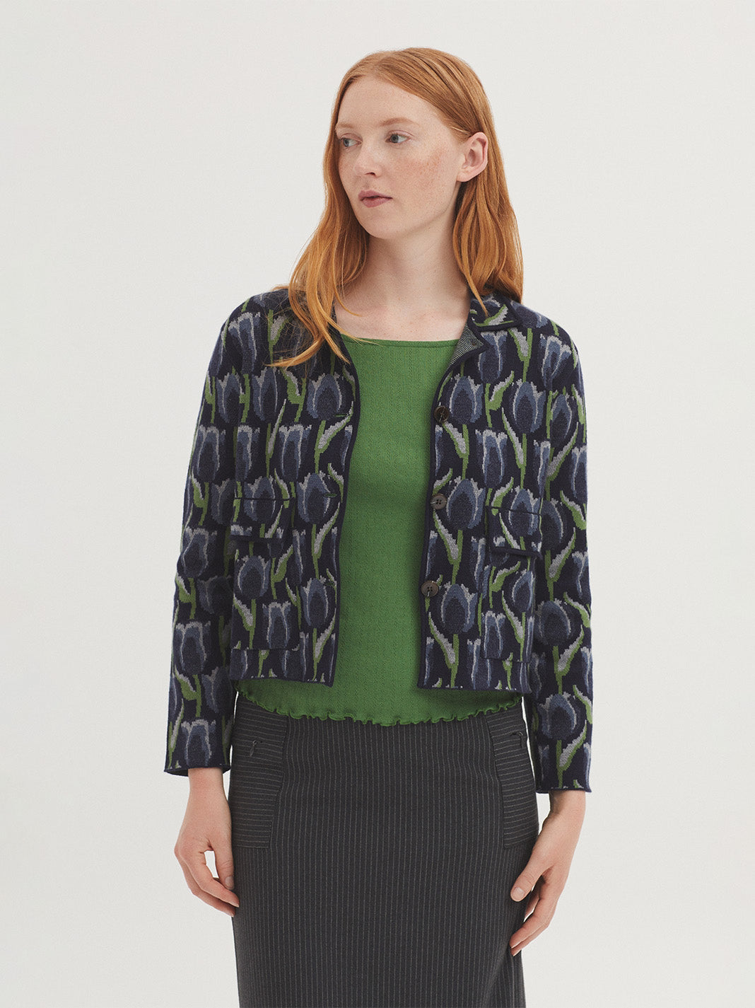 Short navy blue jacquard jacket with tulip design, in light green, ecru light blue colors, shirt collar, front patch pockets and long sleeves.