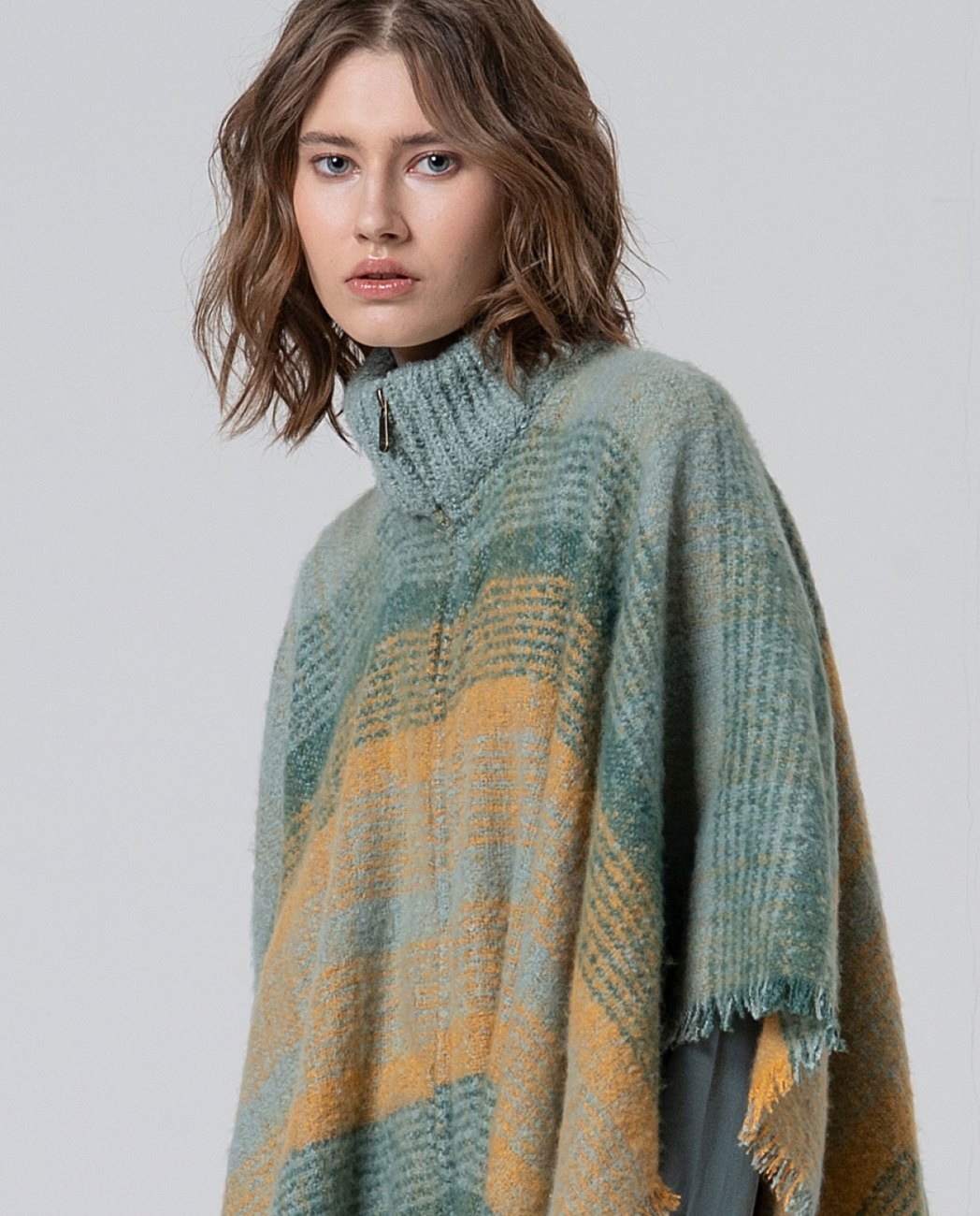 Plaid poncho with fringe inn light blue, green and yellow colors and zip closure