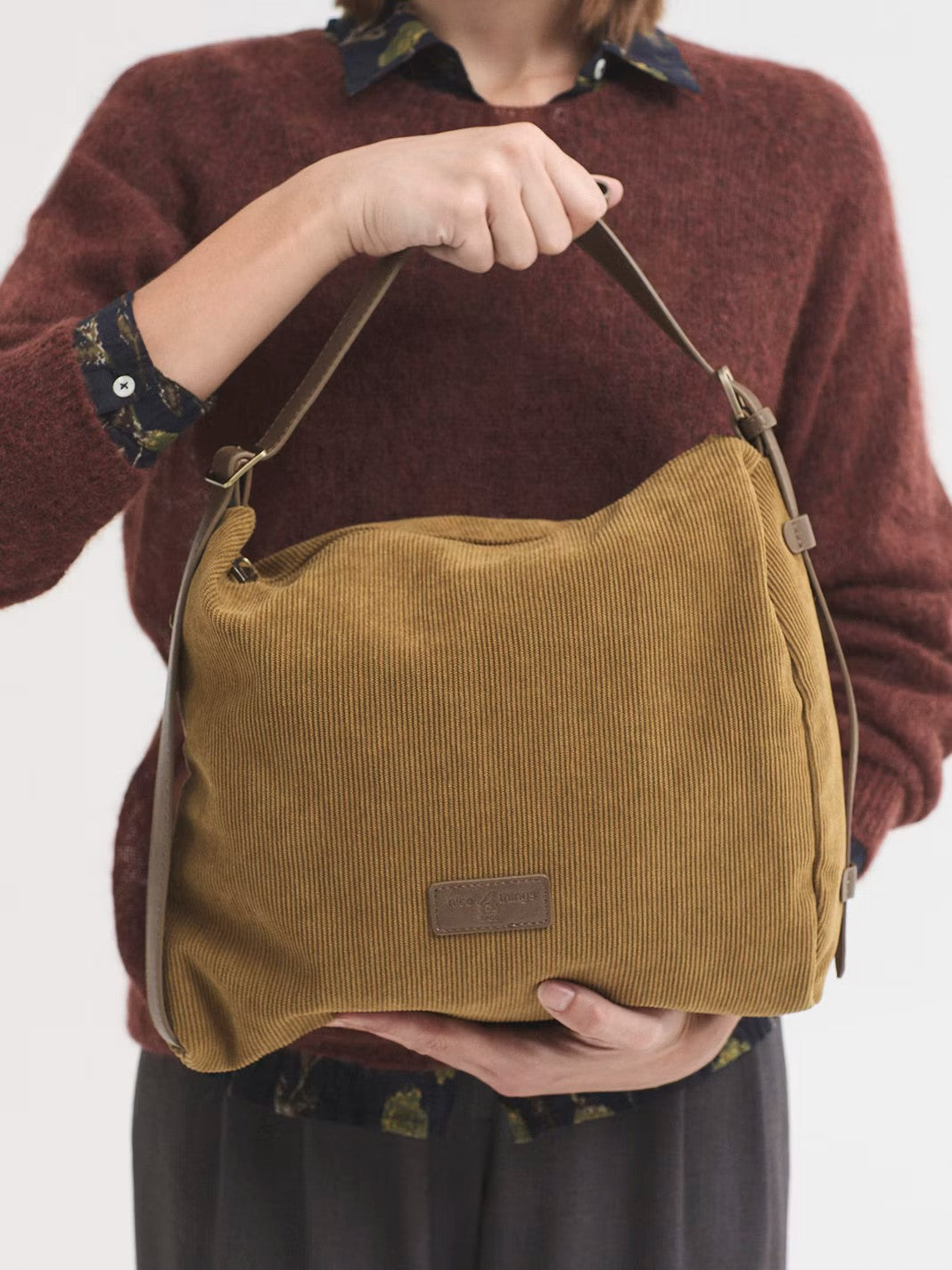 Soft olive corduroy bag with a versatile design so it can be used three ways: as a shoulder bag, crossbody bag and rucksack thanks to its adjustable strap. Featuring a zip top fastening with a pull tab with logo. Inside pockets for organization. With a logo patch in the design, 32 cm long x 28 cm high x 12.5 cm deep.