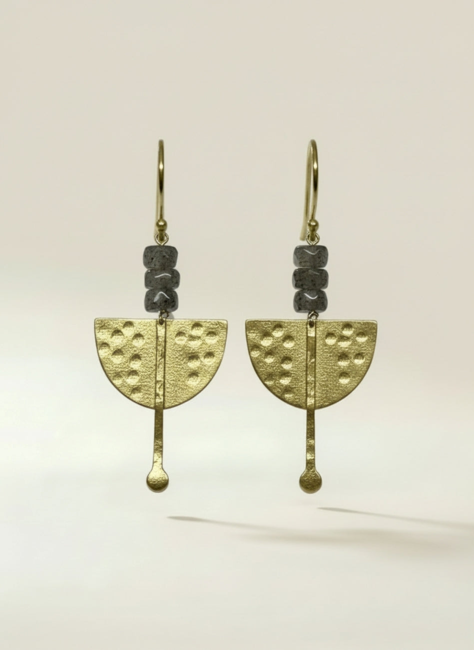A pair of handmade dangle earrings featuring textured gold-toned metal pieces, dark gray stone beads, and a small gold hook, labradorite and gold rhodium