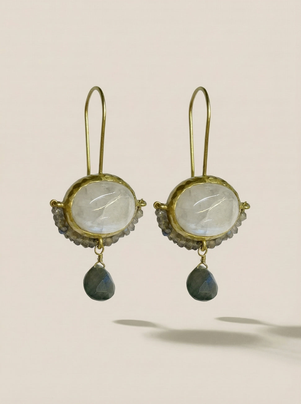 A pair of gold drop earrings featuring oval milky white stones and teardrop-shaped dark gray-green drops, Labradorite cameo and moonstone earrings, in rhodium gold.