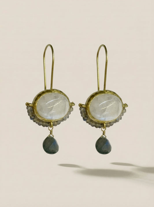 A pair of gold drop earrings featuring oval milky white stones and teardrop-shaped dark gray-green drops, Labradorite cameo and moonstone earrings, in rhodium gold.