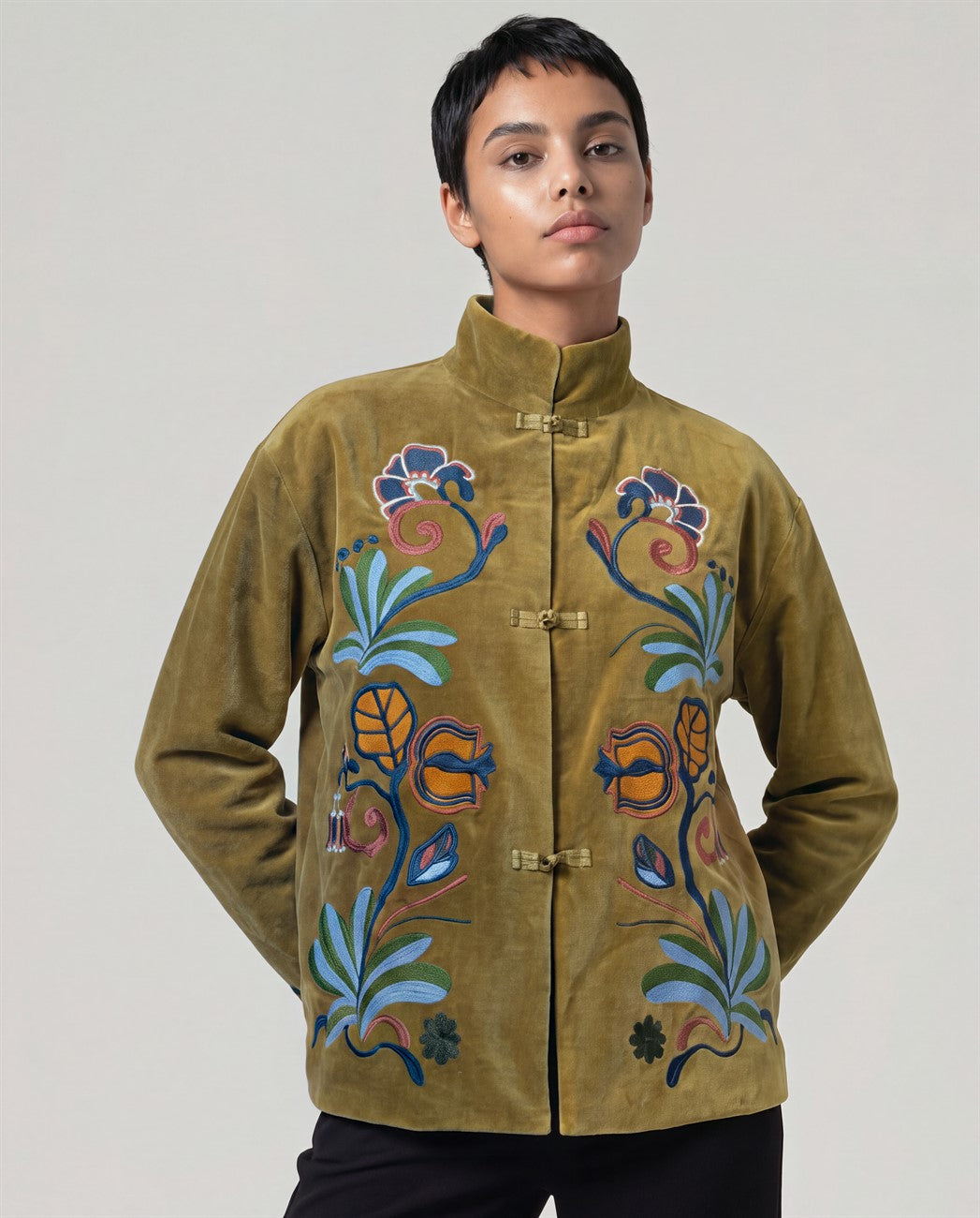 Short mustard velvet jacket with a mandarin collar and knot fastenings. A generous embroidery of flowers, pomegranates and leaves blooms on both sides of the front, wonderfully handmade. Long sleeves. Inner cotton fabric.