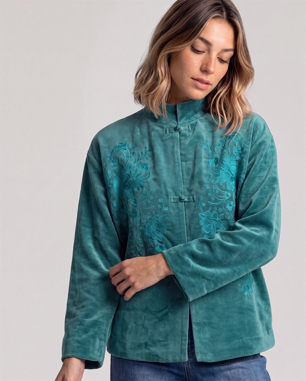 Short petrol velvet jacket with a mandarin collar and knot fastenings. Elegant floral swirls embroidered in the same color as the fabric unfold on both sides of the chest. Long sleeves. Inner cotton fabric.