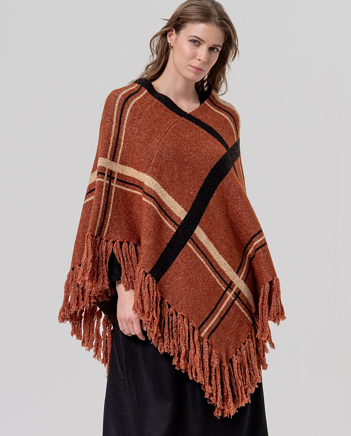 Knit camel poncho with recycled polyester, a V-neckline and generous fringing at the hem. Diagonal tartan jacquard, warm and full-bodied. 