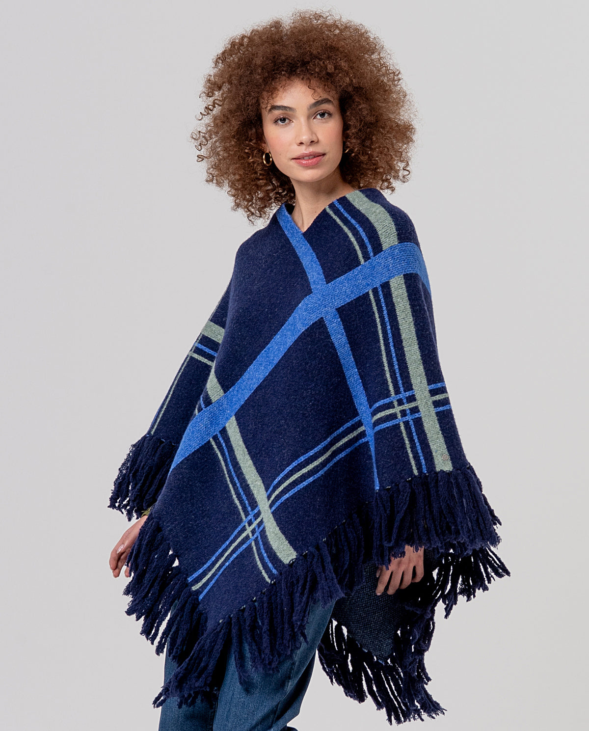 Knit navy poncho with recycled polyester, a V-neckline and generous fringing at the hem. Diagonal tartan jacquard, warm and full-bodied.