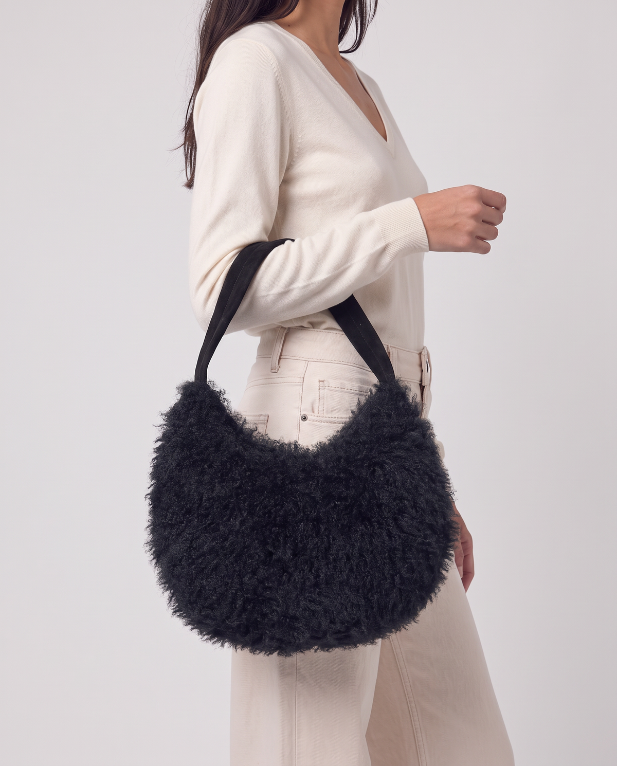Shoulder bag black in long-pile faux fur with a plush feel. Enveloping half-moon silhouette with a thin strap and zip closure, 34cm x 24cm x 10cm