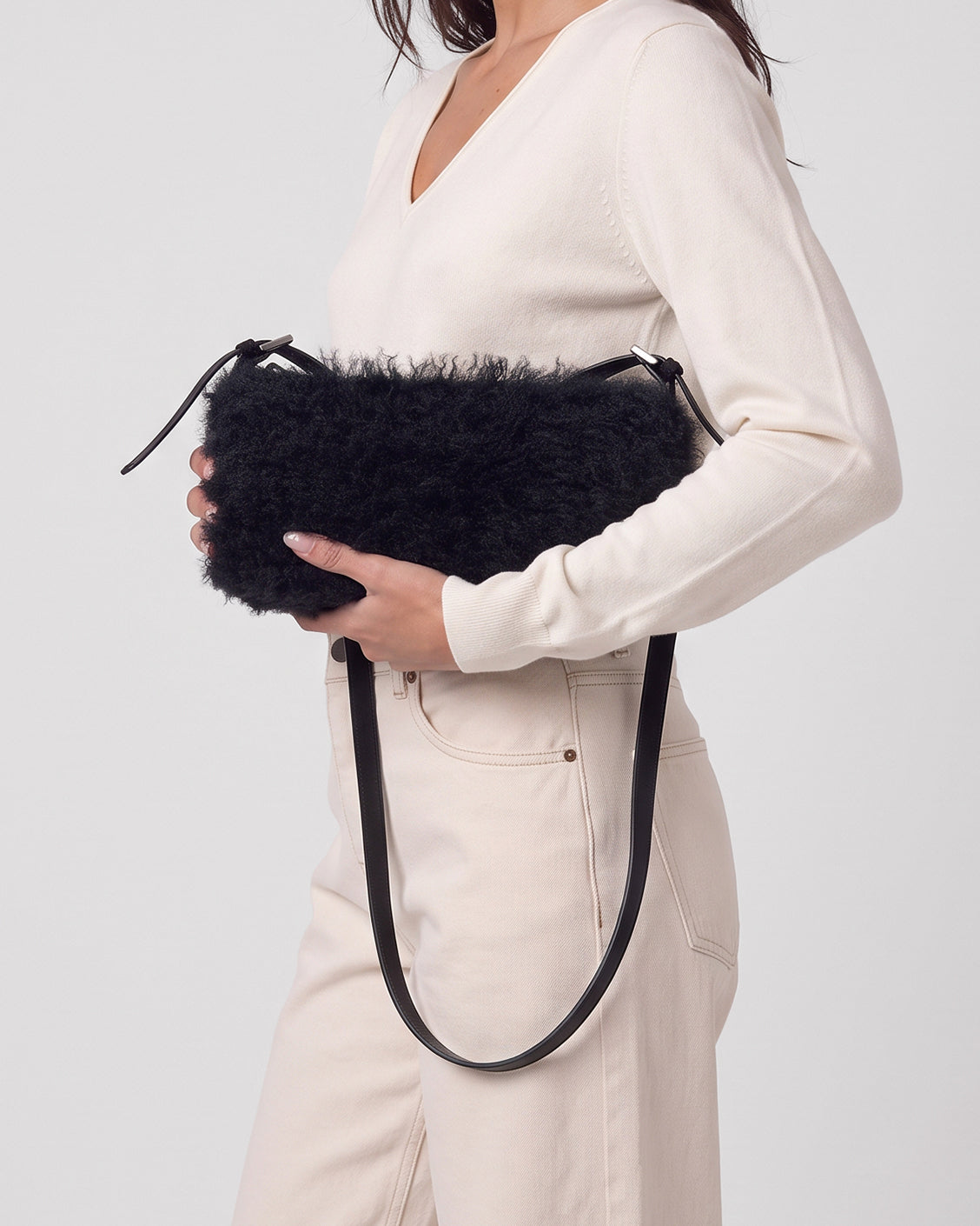 Baguette black bag in long-pile faux fur with a plush feel. Small, elongated shape with a thin adjustable strap and zip closure, 28cm x 16cm x 7cm