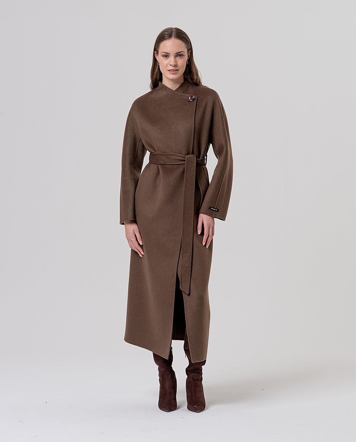 Long dark camel double-breasted wool coat with an asymmetric wrap collar and a belt to define the waist. Decorative button fastening and side pockets