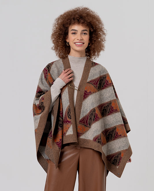 Open beige cape-poncho in warm knit with a pin fastening and contrasting trim. Wave and abstract jacquard in brown, grey mustard and bordeaux colors with a felted texture.