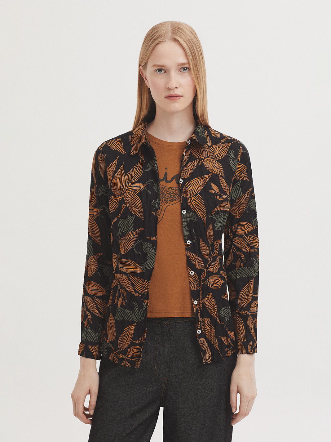 Basic black shirt with jungle print, leaves and panthers in brown and light green colors, in sustainable crinkle cotton fabric, shirt collar and mother-of-pearl button front, long sleeves with vent, cuff and button, complete with matching fabric bag.