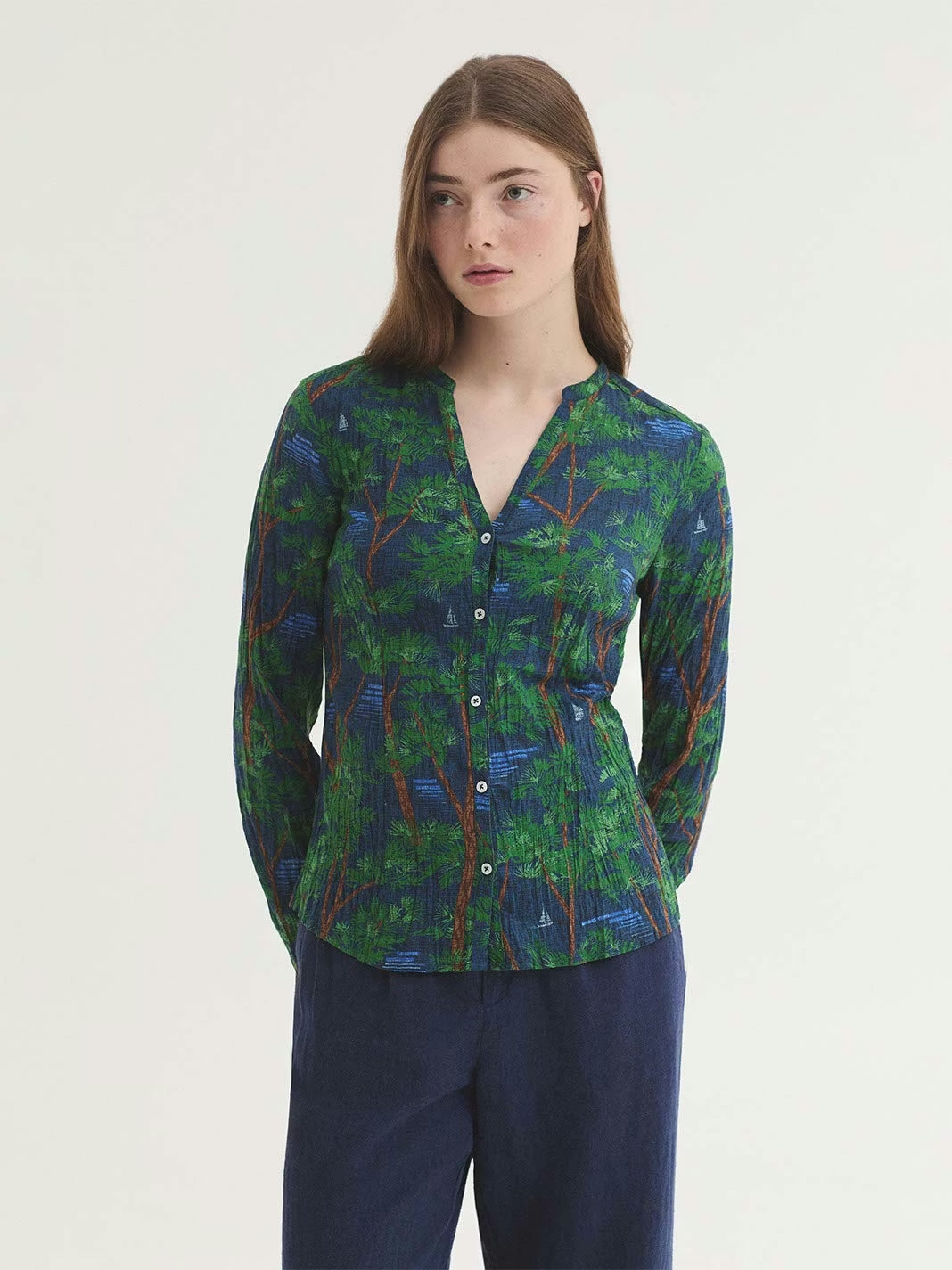 Mandarin colar blue shirt in sustainable crinkle cotton fabric, with Pine Trees wood print, in brown and green colors, mother-of-pearl button front and long sleeves with vent, cuff and button; presented in a self-fabric bag.