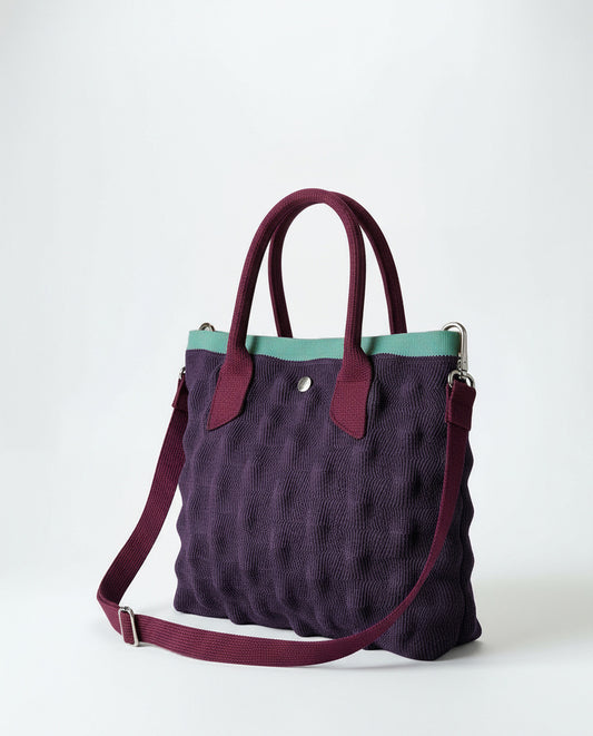 Mini purple knit shopper with a bubble-effect 3D texture. Two short handles and an adjustable - removable crossbody strap, with contrast trim in meant color and a zip closure. 24cm x 19cm x 6cm