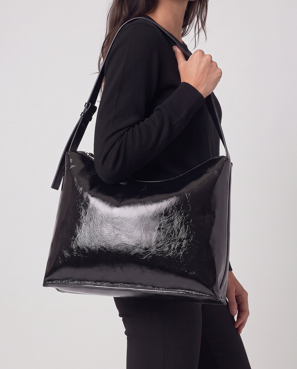 Shoulder black bag in high-shine patent with a smooth feel. Triangular, unstructured shape with a soft drape, thin adjustable strap and zip closure,30cm x 40cm x 1cm