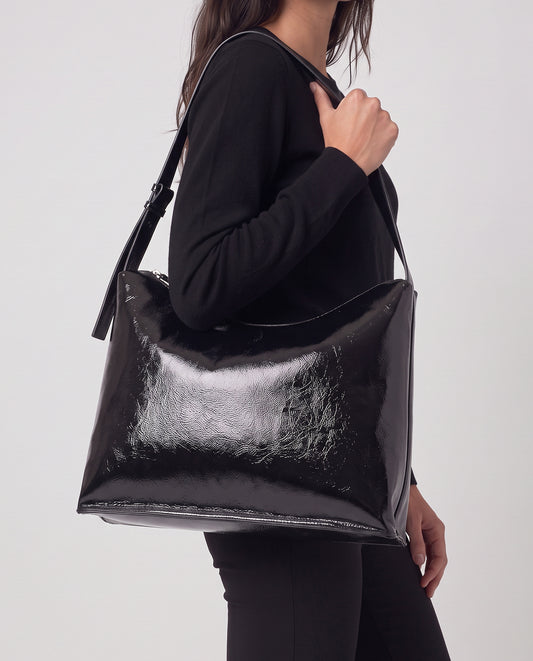 Shoulder black bag in high-shine patent with a smooth feel. Triangular, unstructured shape with a soft drape, thin adjustable strap and zip closure,30cm x 40cm x 1cm