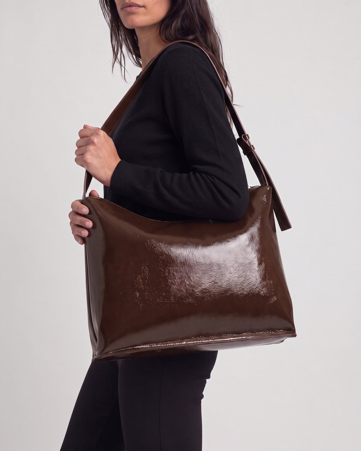 Shoulder chocolate bag in high-shine patent with a smooth feel. Triangular, unstructured shape with a soft drape, thin adjustable strap and zip closure. Inside patch pocked and zip closure pocked, 30cm x 40cm x 1cm