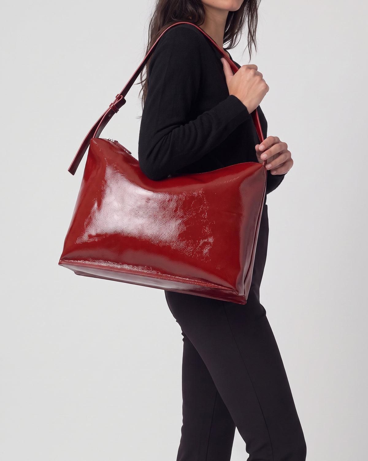 Shoulder bag red in high-shine patent with a smooth feel. Triangular, unstructured shape with a soft drape, thin adjustable strap and zip closure, 30cm x 40cm x 1cm
