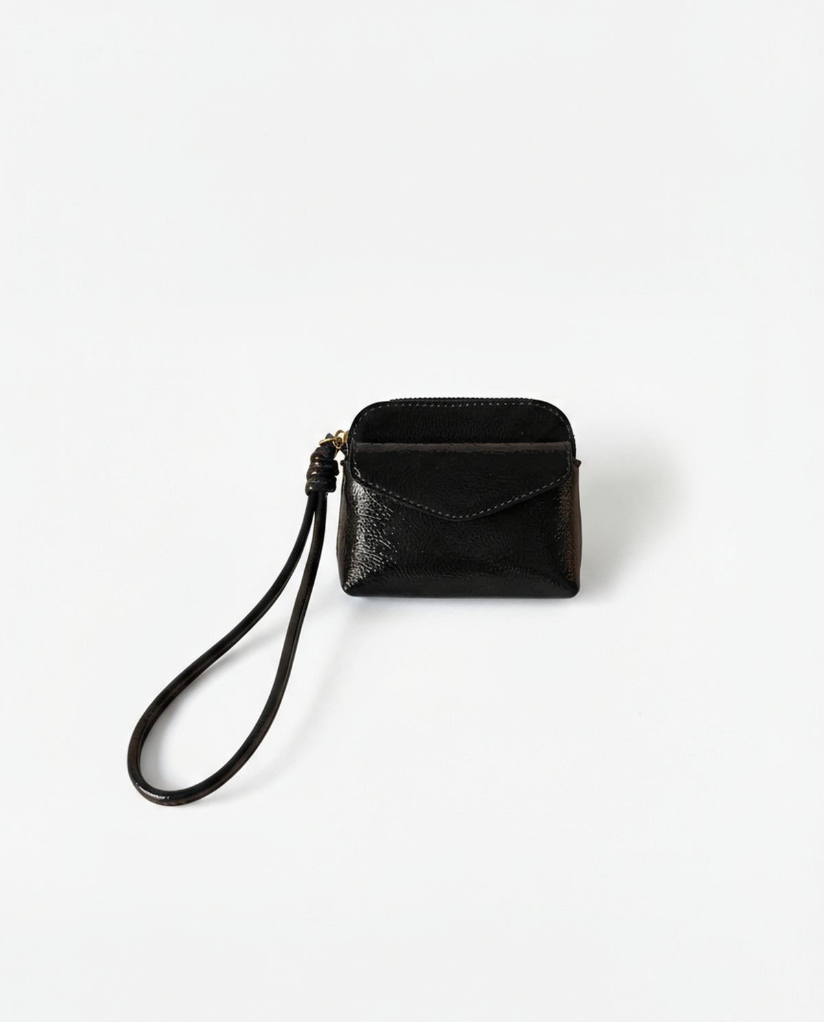 Coin purse black in crinkled patent with an intense shine. Envelope flap and zip closure, with a handy wrist strap. Mini, light format for the essentials. 10cm x 8cm x 2cm