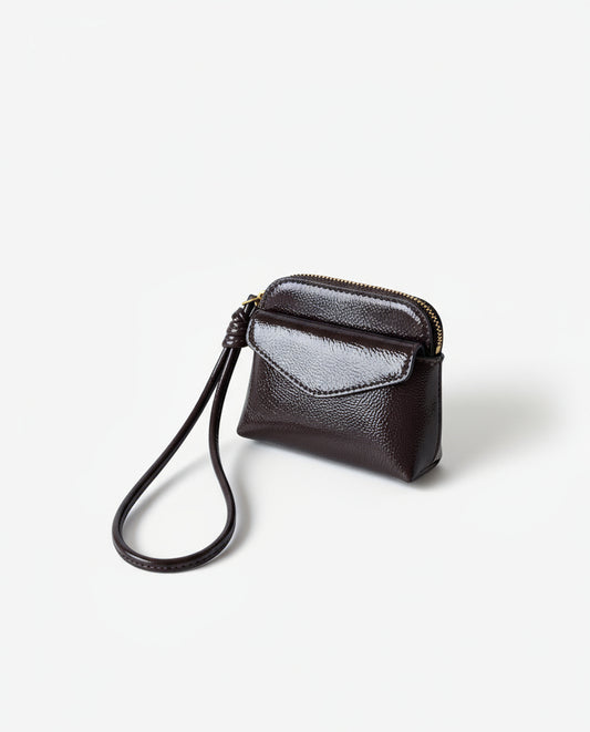 Coin purse chocolate in crinkled patent with an intense shine. Envelope flap and zip closure, with a handy wrist strap. Mini, light format for the essentials. 10cm x 8cm x 2cm