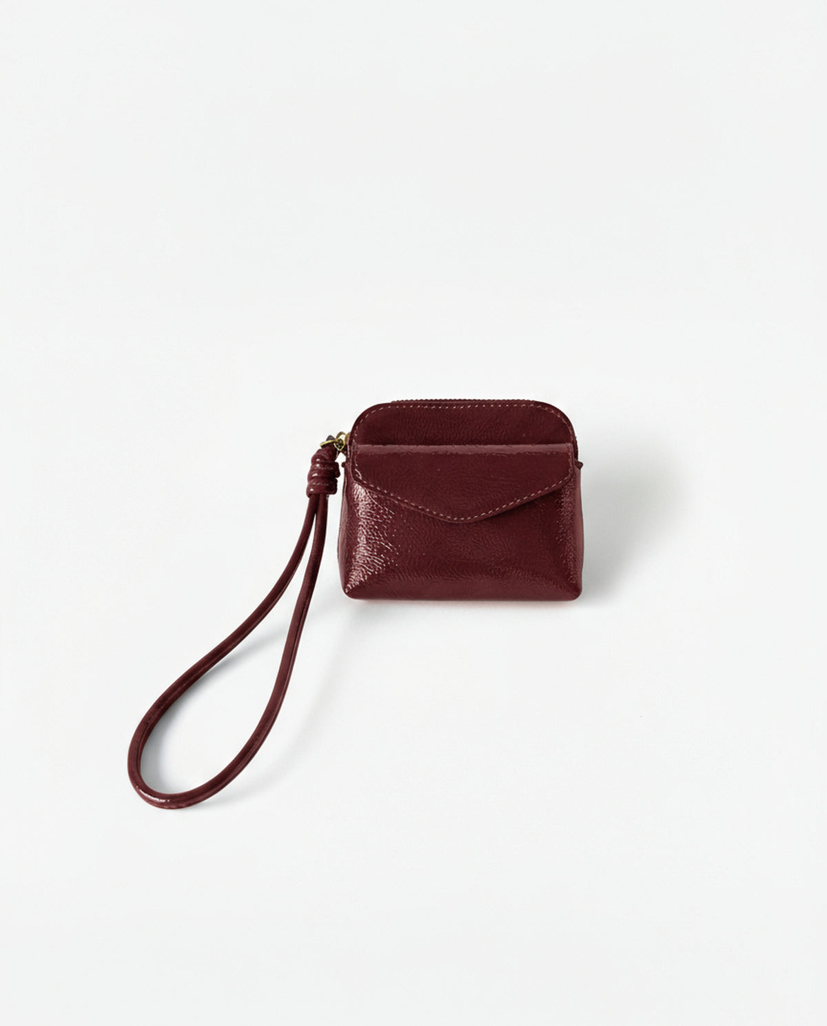 Coin purse red in crinkled patent with an intense shine. Envelope flap and zip closure, with a handy wrist strap. Mini, light format for the essentials. 10cm x 8cm x 2cm