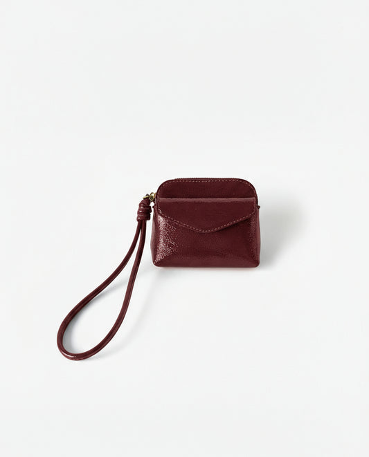 Coin purse red in crinkled patent with an intense shine. Envelope flap and zip closure, with a handy wrist strap. Mini, light format for the essentials. 10cm x 8cm x 2cm