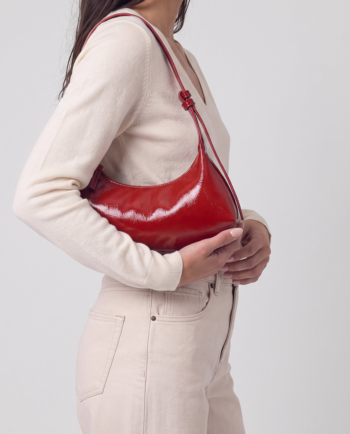 Small red bag in crinkled patent with a lively shine. Half-moon shape with a wide base, adjustable buckled strap and zip closure. Inner zip pocket, 29cm x 10cm x 8 cm