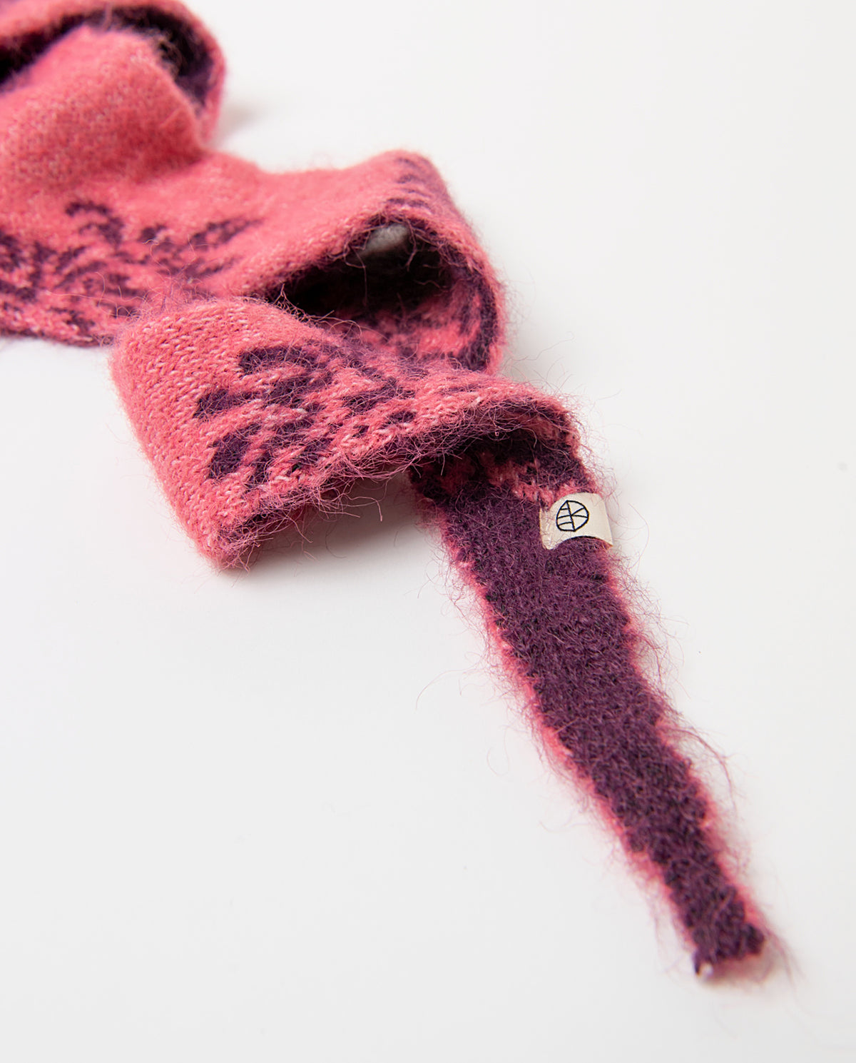 Knit bandana in recycled polyester with a two-tone bordeaux and pink colors jacquard motif, soft and fluffy to the touch. Pointed ends that tie around the neck, 170cm long, 20cm wide
