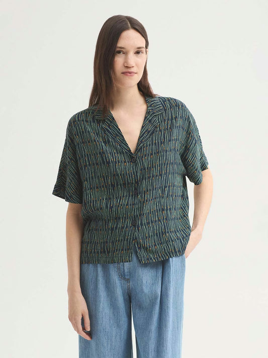 Pine Needles print shirt in viscose navy crêpe, with pine needles in green and dark yellow colors, notch lapels and button front, short sleeves.