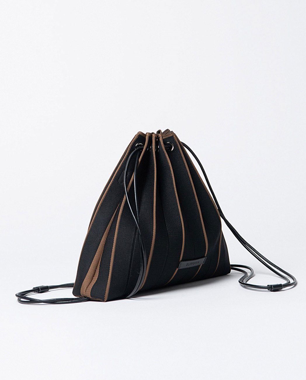Knitted pleated backpack-bag in black and brown colors, closure with cords that slide through eyelets, includes a practical zippered toiletry bag and removable shoulder strap.