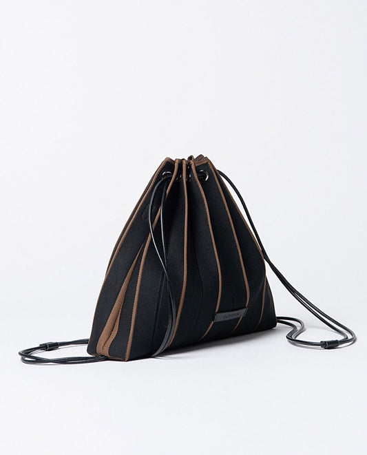 Knitted pleated backpack-bag in black and brown colors, closure with cords that slide through eyelets, includes a practical zippered toiletry bag and removable shoulder strap.