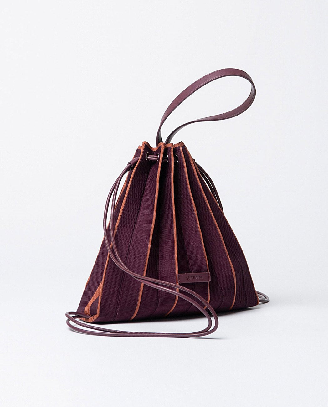 Knitted pleated backpack-bag in bordeaux and orange colors, closure with cords that slide through eyelets,includes a practical zippered toiletry bag and removable shoulder strap.
