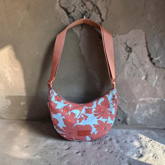 Penelope's flower printed curved crossbody bag, in brown, light turquoise  and a little of orange colors, with zip closure and adjustable strap. Inside pocket. Debossed logo.,composition: 100% Polyester, measurements: 18 cm tall x 26 cm wide x 7 cm deep.
