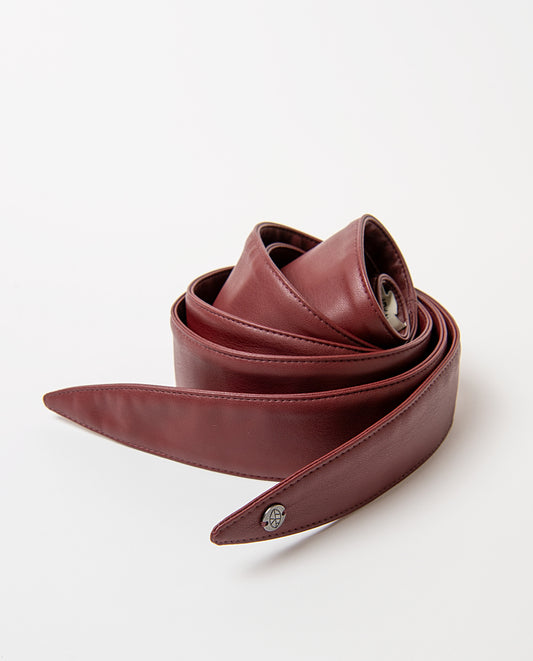 Sash-style bordeaux belt in smooth faux leather, wide and soft to the touch. Pointed ends that tie in a bow, no buckle, with a branded metal rivet. 220cm long, 4,50 - 12,50cm wide