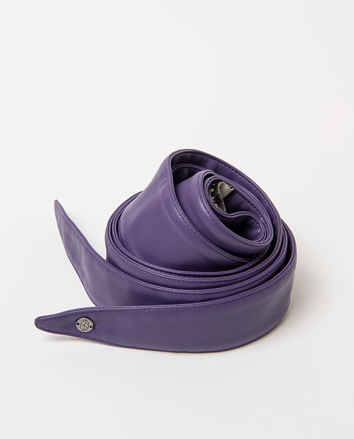 Sash-style purple belt in smooth faux leather, wide and soft to the touch. Pointed ends that tie in a bow, no buckle, with a branded metal rivet.220cm long, 4,50 - 12,50cm wide