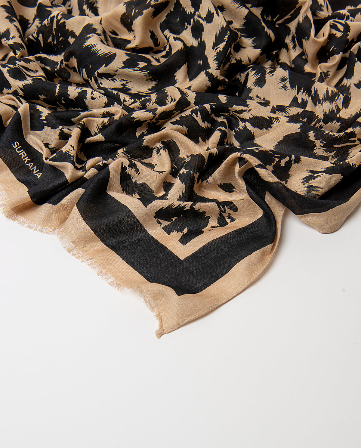 Rectangular black scarf in light viscose with soft drape. Abstract brushed ecru animal print, with a plain border and fringed edge.