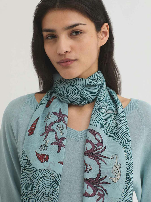 Aegean Sea rectangular viscose print foulard, 70cmx180cm, in turquoise background color, with intense red shells prints and black waves, silk touch.