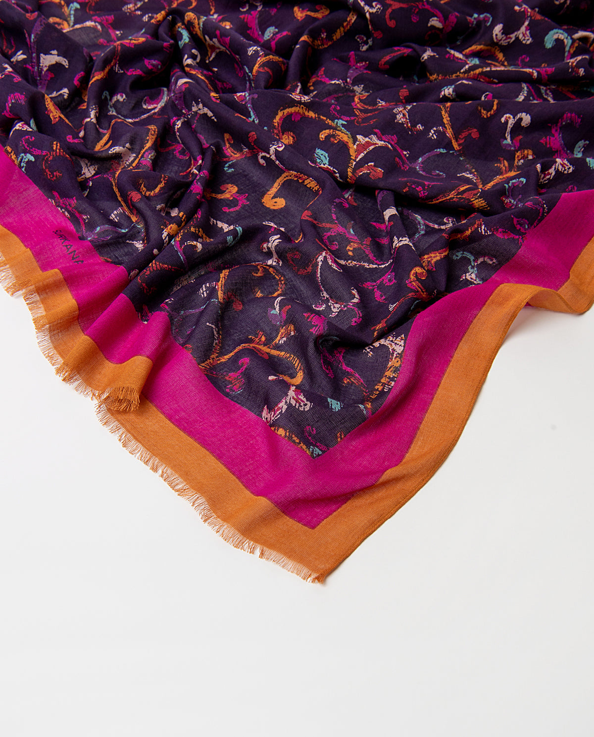 Rectangular purple scarf in light viscose with fluid drape. Abstract arabesque print in fuchsia, orange and light blue colors, with a contrasting banded border and fringe.