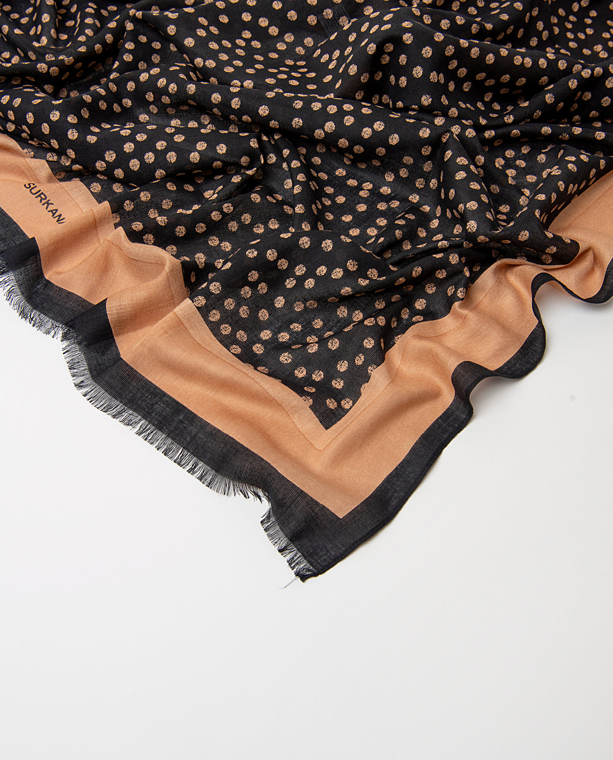 Rectangular black scarf in light, fluid viscose. Irregular beige polka-dot print with a batik feel, contrasting plain border and fringe.