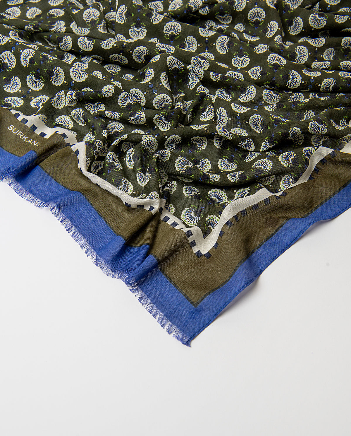 Rectangular khaki scarf in light viscose. Delicate ditsy floral print i ecru, blue and light green colors, with an artisan feel, contrasting banded border and fringe.