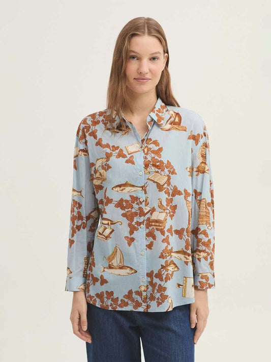 Shirt in sustainable light blue cotton fabric, Midsummer Books print, like fishes, leaves, boats,in cinnamon color, with shirt collar, mother-of-pearl button front and long sleeves with vent, cuff and button.